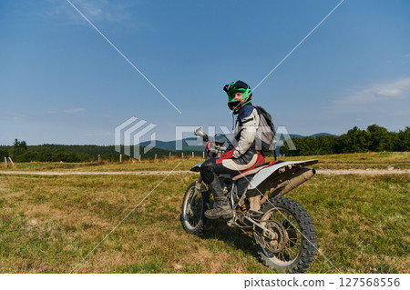 A motorcyclist equipped with professional gear, rides motocross on perilous meadows, training for an upcoming competition. 127568556