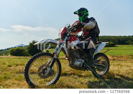 A motorcyclist equipped with professional gear, rides motocross on perilous meadows, training for an upcoming competition. 127568566