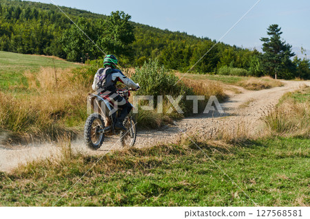 A professional motocross rider exhilaratingly riding a treacherous off-road forest trail on their motorcycle. A professional motocross rider exhilaratingly riding a treacherous off-road forest trail on their motorcycle. 127568581