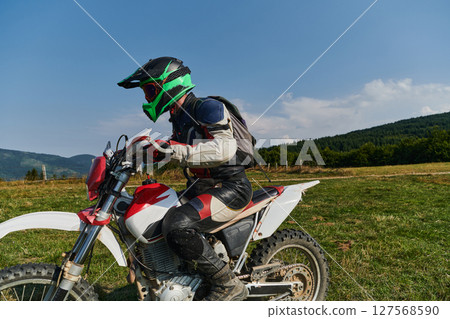 A motorcyclist equipped with professional gear, rides motocross on perilous meadows, training for an upcoming competition. 127568590