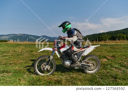 A motorcyclist equipped with professional gear, rides motocross on perilous meadows, training for an upcoming competition. 127568592