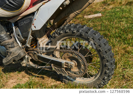 Close up photo of a professional motocross rider in action, showcasing the tire and various components of the motorcycle as they navigate the challenging off-road terrain with speed and precision. 127568596