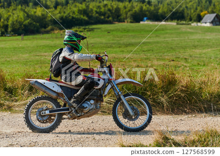 A professional motocross rider exhilaratingly riding a treacherous off-road forest trail on their motorcycle. 127568599