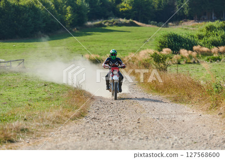 A professional motocross rider exhilaratingly riding a treacherous off-road forest trail on their motorcycle. 127568600