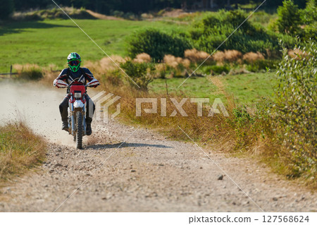 A professional motocross rider exhilaratingly riding a treacherous off-road forest trail on their motorcycle. A professional motocross rider exhilaratingly riding a treacherous off-road forest trail on their motorcycle. 127568624
