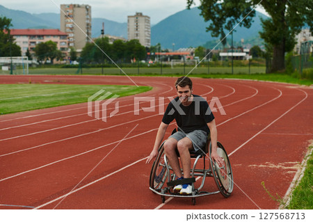 A person athlete with disability in a wheelchair racing on an outdoor track. A person athlete with disability in a wheelchair racing on an outdoor track. 127568713