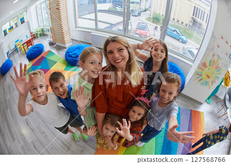 Children in a preschool institution standing in the classroom together with the teacher 127568766