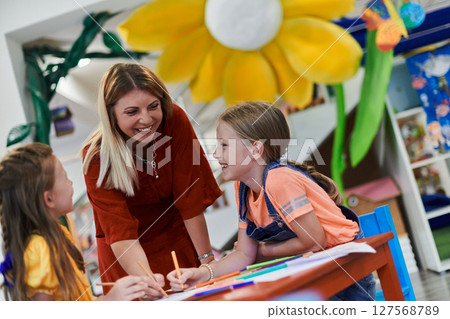 Creative kids during an art class in a daycare center or elementary school classroom drawing with female teacher. 127568789