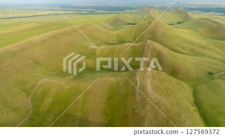 Green hilly terrain on a bright sunny morning. 127569372