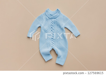 Baby knitted onesie on beige background. Fashion newborn clothes. Flat lay top view. Wool kid soft clothing. Infant trendy bodysuit made of organic eco friendly cotton. Children wardrobe. Baby garment 127569615