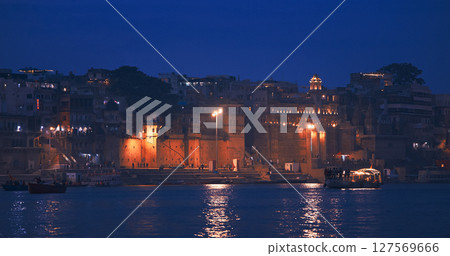 Varanasi, Uttar Pradesh, India. Chousatti Ghat and Rana Mahal Ghat in night time illumination lights. Boats floating near old palace in Rajasthani style. Cinematic Camera movement moving along 127569666