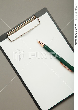 Black tablet with piece of empty paper and pen on grey background. Vertical photo 127569823