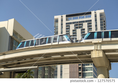City train car on high railroad over street traffic between skyscraper buildings in modern American megapolis. Urban transportation in downtown district of Miami Brickell in Florida USA City train car on high railroad over street traffic between skyscraper buildings in modern American megapolis. Urban transportation in downtown district of Miami Brickell in Florida USA 127570575