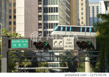 City train car on high railroad over street traffic between skyscraper buildings in modern American megapolis. Urban transportation in downtown district of Miami Brickell in Florida USA City train car on high railroad over street traffic between skyscraper buildings in modern American megapolis. Urban transportation in downtown district of Miami Brickell in Florida USA 127570576