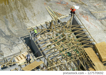 Builders working on roof construction of unfinished residential house with wooden frame structure in Florida suburban area. Housing development concept 127570692