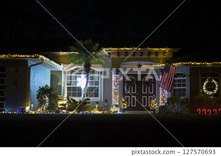 Brightly illuminated christmas decorations on front yard of florida family home. Outside decor for winter holidays 127570693