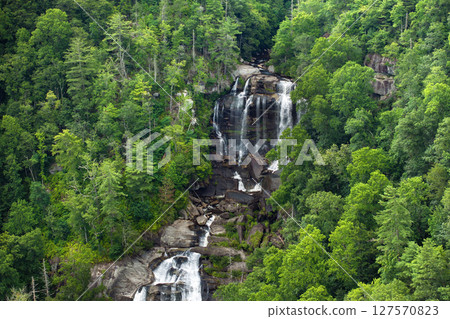 Beautiful landscape of high waterfall with falling down clear water from rocky boulders between green lush woods. Whitewater Falls in Nantahala National Forest, North Carolina, USA Beautiful landscape of high waterfall with falling down clear water from rocky boulders between green lush woods. Whitewater Falls in Nantahala National Forest, North Carolina, USA 127570823