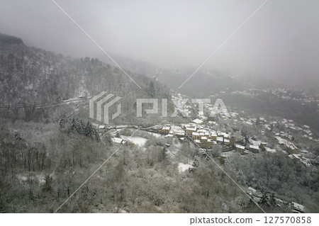 Aerial winter landscape of dense historic center of Thiers town in Puy-de-Dome department, Auvergne-Rhone-Alpes region in France. Rooftops of old buildings and narrow streets at snowfall 127570858
