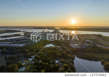 Aerial view of wood processing factory with smoke from production process polluting atmosphere at plant manufacturing yard. Industrial site at sunset 127570862