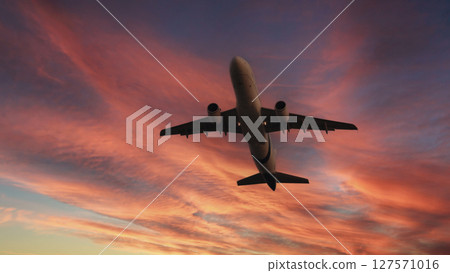 Airplane in the sky. Airplane in flight at sunset or evening sky. Commercial airliner silhouette in the colorful evening or night moon skies. Aircraft symbol of travel adventure global connectivity. 127571016