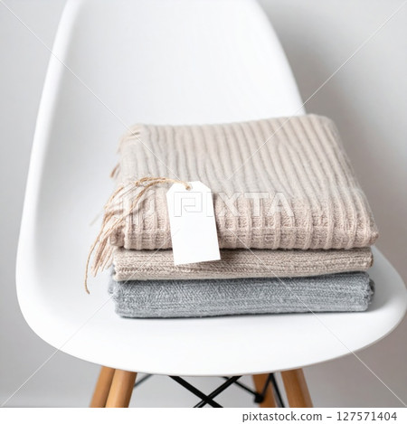 Beige and Gray Knit Scarves Stacked on White Chair Beige and Gray Knit Scarves Stacked on White Chair 127571404