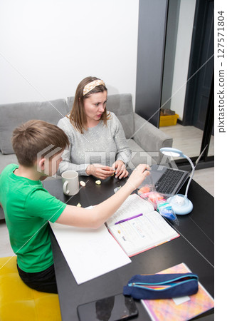 Engaging study session between mother and child at home in a modern living room, enjoying learning with hands on activities on a bright afternoon Engaging study session between mother and child at home in a modern living room, enjoying learning with hands on activities on a bright afternoon 127571804