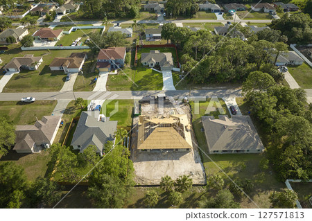 Aerial view of suburban private house wit wooden roof frame under construction in Florida quiet rural area 127571813