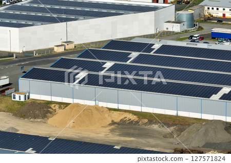 Aerial view of solar power plant with blue photovoltaic panels mounted on industrial building roof for producing green ecological electricity. Production of sustainable energy concept 127571824