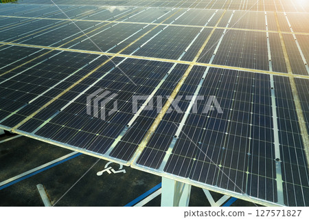 Aerial view of solar panels installed as shade roof over parking lot for parked cars for effective generation of clean electricity. Photovoltaic technology integrated in urban infrastructure Aerial view of solar panels installed as shade roof over parking lot for parked cars for effective generation of clean electricity. Photovoltaic technology integrated in urban infrastructure 127571827