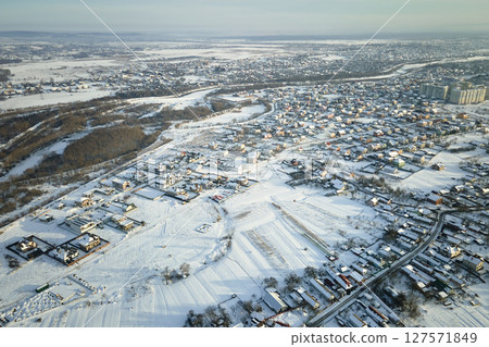 Aerial view of residential houses with snow covered roofops in suburban rural town area in winter Aerial view of residential houses with snow covered roofops in suburban rural town area in winter 127571849