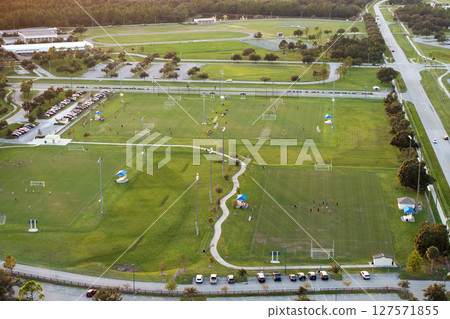 Aerial view of public sports park with children engaged in football game on grass stadium at sunset. Active way of life concept 127571855