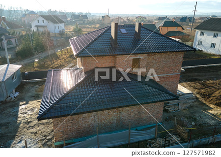 Aerial view of house roof top covered with ceramic shingles. Tiled covering of building under construction 127571982