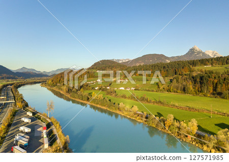 Aerial view of highway interstate road with fast moving traffic near big river in Alps mountains 127571985