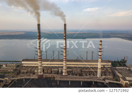 Aerial view of high chimney pipes with grey smoke from coal power plant. Production of electricity with fossil fuel. 127571992