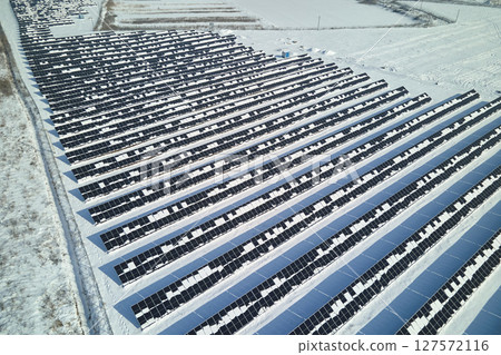 Aerial view of electrical power plant with solar panels covered with snow melting down in winter end for producing clean energy. Concept of low effectivity of renewable electricity in northern region Aerial view of electrical power plant with solar panels covered with snow melting down in winter end for producing clean energy. Concept of low effectivity of renewable electricity in northern region 127572116