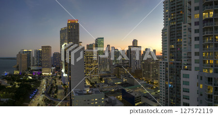 Aerial view of downtown district of of Miami Brickell in Florida, USA. Brightly illuminated high skyscraper buildings and street with cars and Metrorail traffic in modern american midtown 127572119