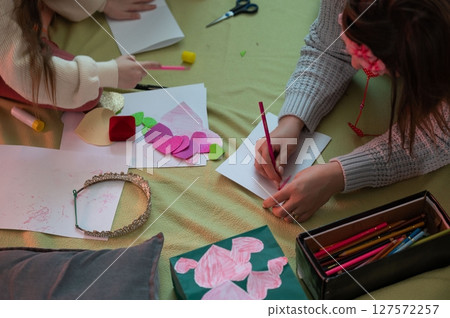 A woman and child create handmade cards and decorations together, fostering creativity and bonding. 127572257