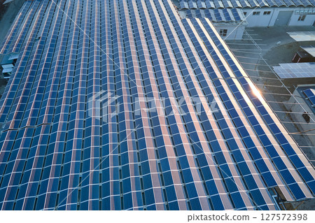 Aerial view of blue photovoltaic solar panels mounted on industrial building roof for producing green ecological electricity. Production of sustainable energy concept Aerial view of blue photovoltaic solar panels mounted on industrial building roof for producing green ecological electricity. Production of sustainable energy concept 127572398