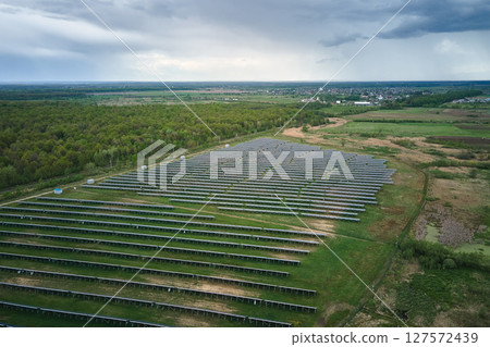Aerial view of big sustainable electric power plant with many rows of solar photovoltaic panels for producing clean ecological electrical energy. Renewable electricity with zero emission concept Aerial view of big sustainable electric power plant with many rows of solar photovoltaic panels for producing clean ecological electrical energy. Renewable electricity with zero emission concept 127572439