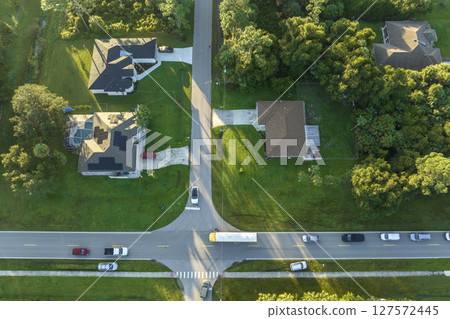 Aerial view of american yellow school bus picking up children at sidewalk bus stop for their lessongs in early morning. Public transportation in the USA 127572445