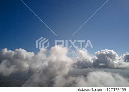 Aerial view from airplane window at high altitude of earth covered with white puffy cumulus clouds 127572469