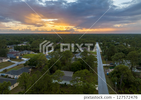 Aerial landscape view of suburban private houses between green palm trees in Florida quiet rural area at sunset 127572476