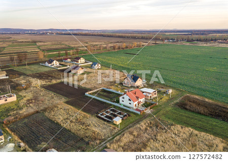 Aerial landscape of small town or village with rows of residential homes and green trees. Aerial landscape of small town or village with rows of residential homes and green trees. 127572482