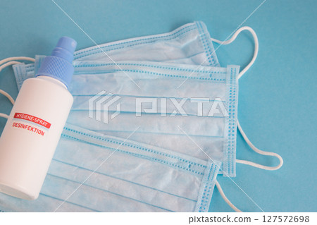 Desinfection spray and medical mask for hygiene on the blue background with place for text. Antibacterial, against pollution or virus protection.  127572698