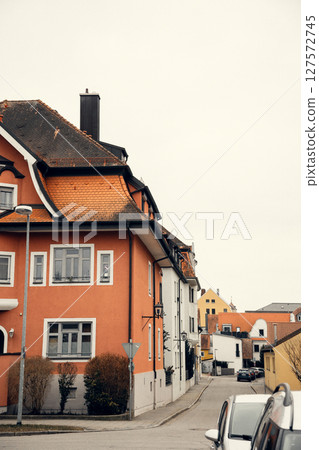A European street lined with historic buildings featuring red-tiled roofs and vibrant facades. The 127572745