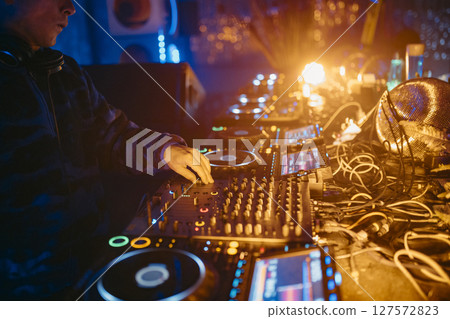Close up view of a dj's hands playing the mixer while performing in a music festival. Close up view of a dj's hands playing the mixer while performing in a music festival. 127572823