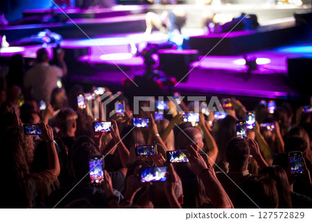 Audience holding up cell phones to record event 127572829