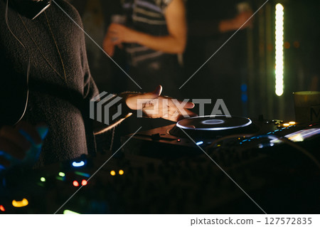 Close up view of a dj's hands playing the mixer while performing in a music festival. Close up view of a dj's hands playing the mixer while performing in a music festival. 127572835