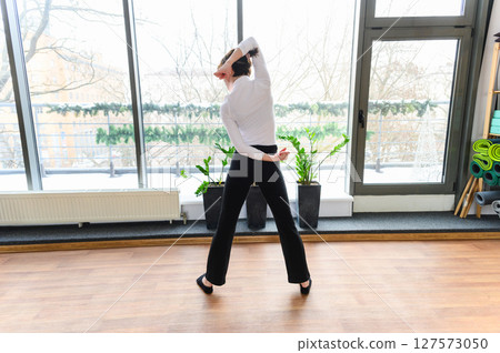 Woman in graceful dance stretch pose near panoramic window. Woman in graceful dance stretch pose near panoramic window. 127573050