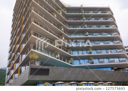 Modern seaside hotel with layered balconies and potted plants. Architecture, coastal tourism and contemporary urban lifestyle. 127573693